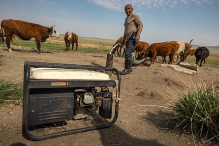 A herder runs a pump to draw groundwater for his cattle