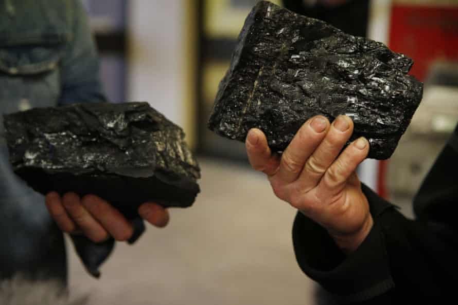Two coalminers hold up souvenirs of their last day of work.