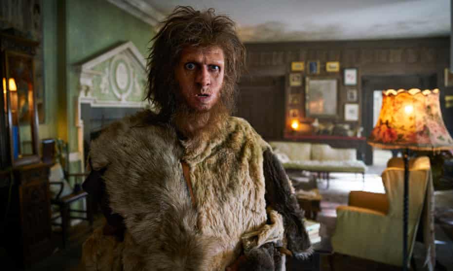 Still from the TV series Ghosts, showing Robin the Caveman in a living room