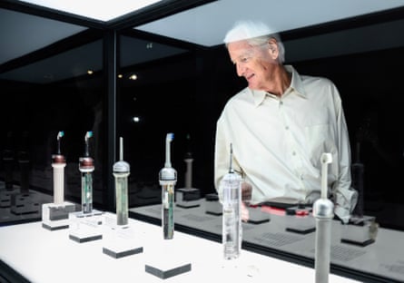 James Dyson stands next to a glass case containing prototype electric toothbrushes
