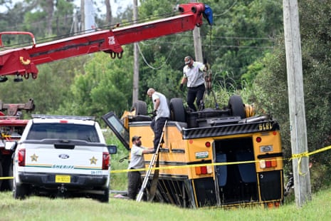 A vehicle recovery crew work to right an overturned school bus