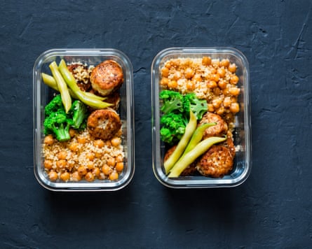 two lunch boxes side by side filled with chickpeas, broccoli, green beans and meatballs