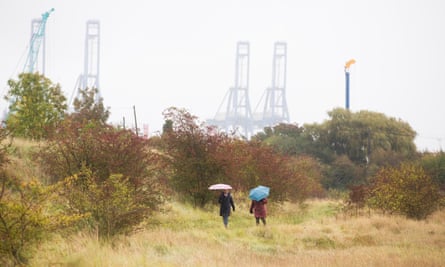 Two figures holding umbrellas walk in the nature reserve
