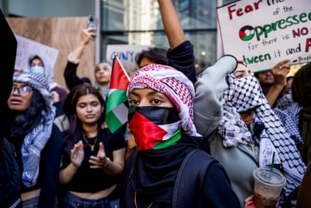 Young people wearing keffiyeh and holding Palestinian flags and signs.