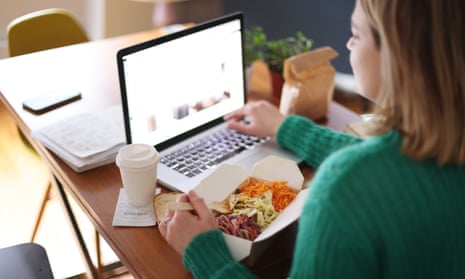 Woman eating takeaway food while working on her laptop