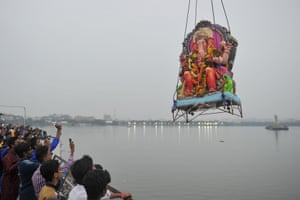 Hyderabad, India  A crowd watches on as as workers use a crane to immerse a statue of Ganesh in the Hussain Sagar Lake on the ninth day of the Ganesh Chaturthi festival