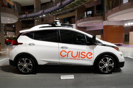 A white car mounted with sensors. Bright orange letters on its side read 'Cruise'