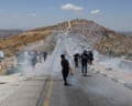 Palestinian landowners, journalists and protesters run from tear gas fired by Israeli security forces blocking a road leading to a newly built Israeli settlement near Dura in the West Bank in June.