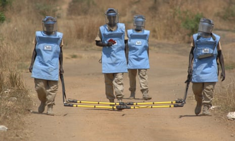 A specialist group of deminers use a piece of scanning equipment known as a broadloop to scan and mark a road in South Sudan suspected of being mined.