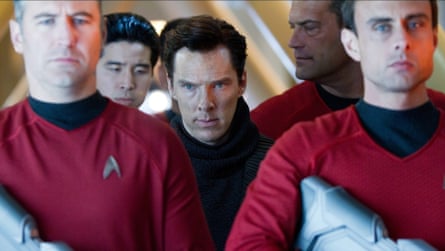 A severe looking man surrounded by Starfleet crew.