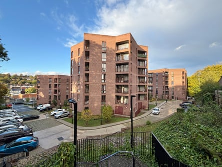 Red brick buildings surrounded by lots of greenery and a car park