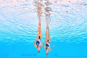 Two swimmers diving such that they appear to be standing upside down underwater