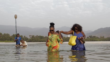 Two women wade through a river