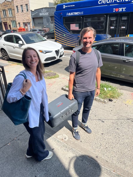 Arianna and Ted Moore, each holding one handle of a large battery, smile for the camera