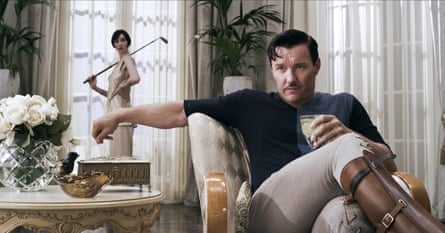 Joel Edgerton with moustache, sitting in a chair drinking and wearing jodphurs and riding boots