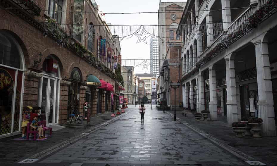 A woman walks down an otherwise deserted street in Wuhan.