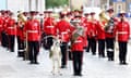 Men in red military uniform and a goat stand to attention