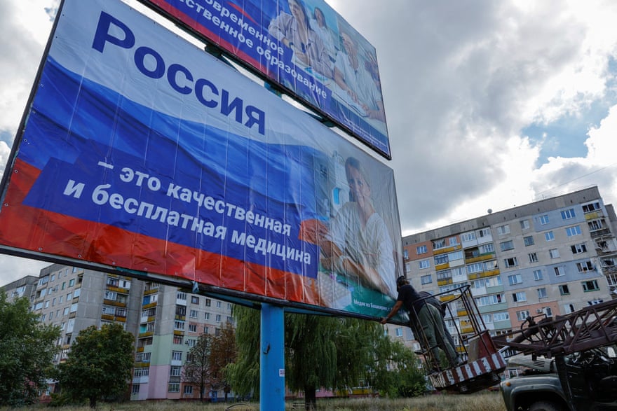 Workers attach banners displaying pro-Russian slogans in Lysychansk, the Luhansk city controlled by pro-Russian forces