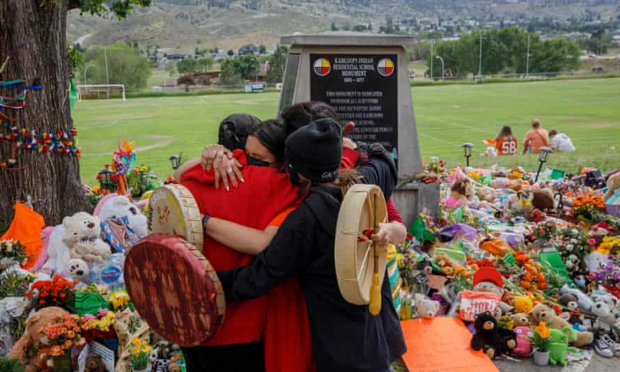 Members of the Mosakahiken Cree Nation hug in front of a makeshift memorial at the former Kamloops Indian Residential School to honor the 215 children whose remains have been discovered buried near the facility, in British Columbia.