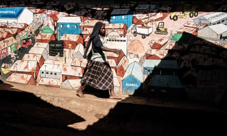 A woman walks past graffiti drawn on the wall in the Kibera slum in Nairobi, on 16 April 2019. 