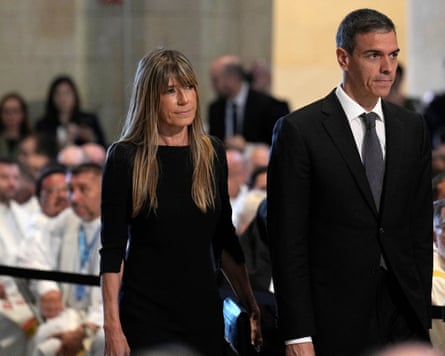Pedro Sánchez and Begoña Gómez walk down the aisle at a mass. They are both dressed in black; she has long blond hair with a fringe.