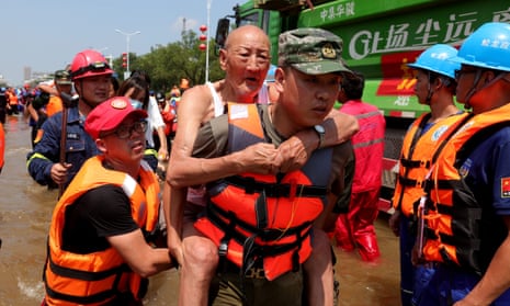 Rescuers move people out of a flooded zone as part of an evacuation effort in Weihui city in central China’s Henan province on 26 July.