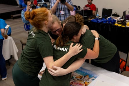 a group of people wearing hunter green t-shirts hugs each other