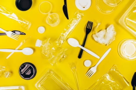Top view of black and white plastic containers and utensils arranged on vivid yellow background
