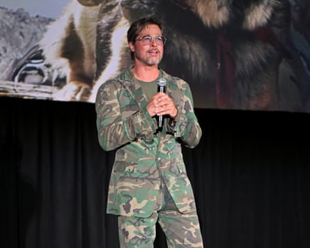 Brad Pitt in a camo suit holding a microphone