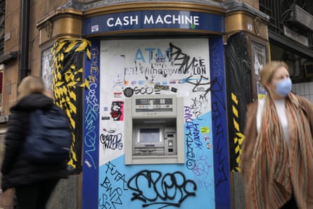 Shoppers walk past a graffitied cash machine on Oxford Street in London.