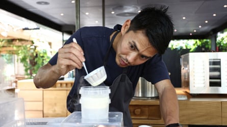 A man looking intently at kitchen equipment as he practises preparing a dish