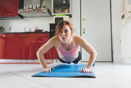 Young woman doing pushups on her kitchen floor