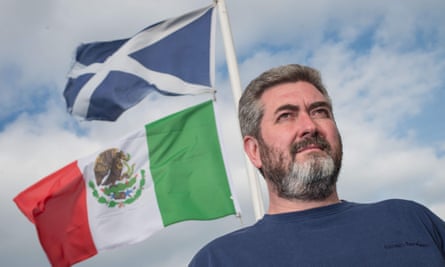 Trump’s neighbour David Milne poses for a photograph beside the Mexican flag and the saltire flying from the top of his house