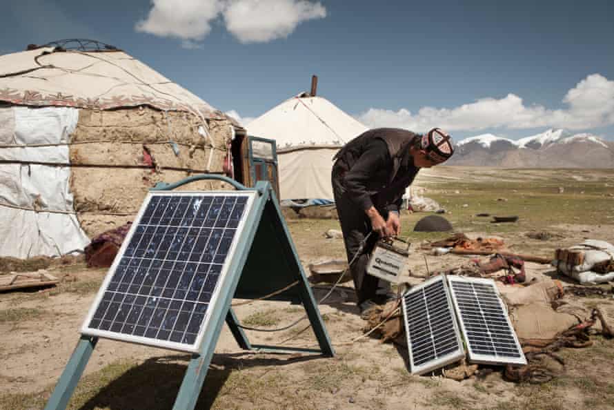A Kyrgyz man installs solar panels that charge car batteries to provide electricity, mainly for light bulbs and radios, Wakhan, Afghanistan.