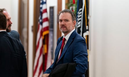 Jamieson Greer talks to other men in suits with American flags behind them