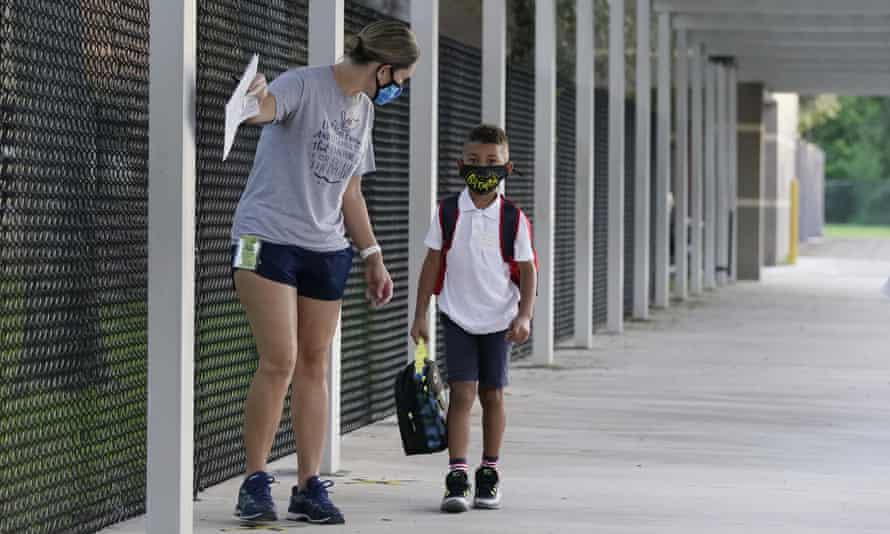 A volunteer escorts a masked freshman into a classroom on the first day of school in Davie in October 2020.