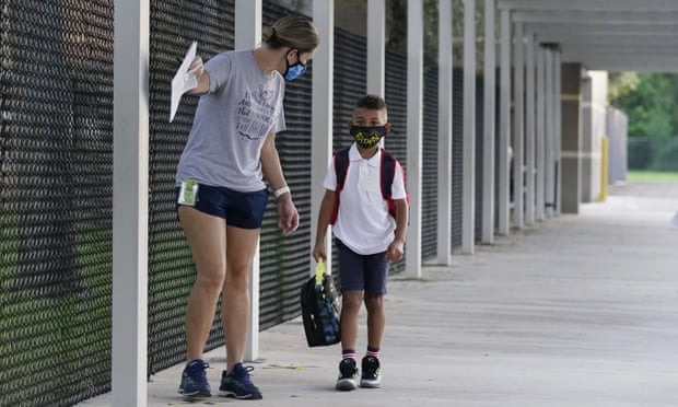 A volunteer escorts a first grader wearing a mask to a classroom on the first day of school in Davie in October 2020.