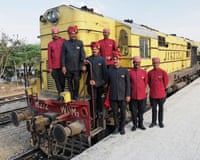 Indian Railways staff wearing bandhgala jackets stand in front of a train