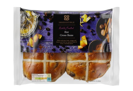 Four co-op hot cross buns in a semi transparent packet with a purple and black label over the top half