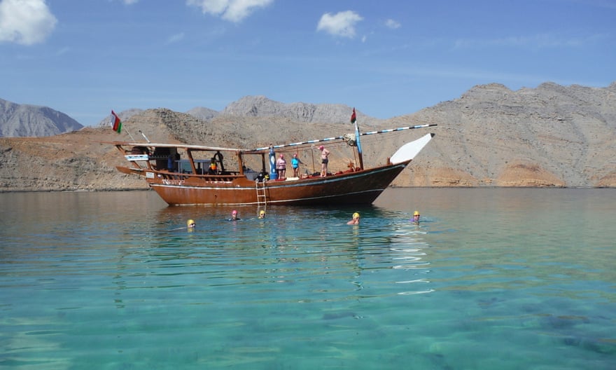 Tourists onboard and around the dhow as part of the Oman fjords swimming holiday