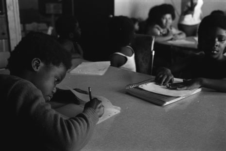 Children sitting at school desks write in exercise books.