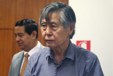 An older man wearing a blue button shirt with no tie.