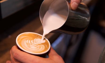 A barista makes latte art with the foam