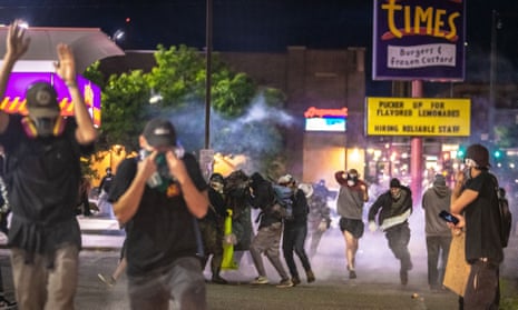 A crowd of Black Lives Matter protesters runs from pepper ball shots from riot police in Denver in May 2020.