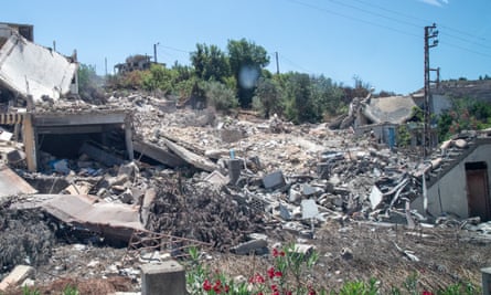 Piles of rubble, with the shell of a garage and a doorway in a wall visible