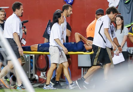 Marco Asensio has his head in his hands as he is carried from the pitch.