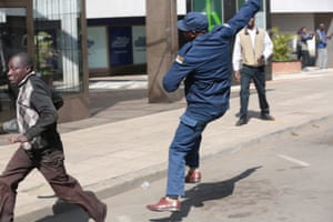 A man runs away from a Zimbabwe Republic Police officer during clashes in Harare.