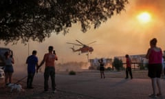 Wildfire burns on the island of RhodesPeople look at a firefighting helicopter filling water from a pool, as a wildfire burns in the village of Gennadi, on the island of Rhodes, Greece, 25 July  2023.  