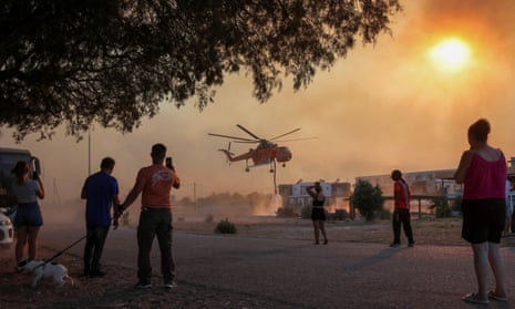 Wildfire burns on the island of RhodesPeople look at a firefighting helicopter filling water from a pool, as a wildfire burns in the village of Gennadi, on the island of Rhodes, Greece, 25 July 2023.