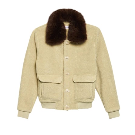 A beige short jacket with a brown furry collar and two pockets on the front on a white background